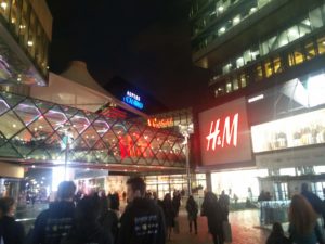 An entrance to the Westfield Center, showing numerous shop signs lit up