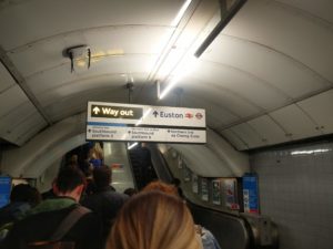 A crowd of people waiting to get onto the escalator to head up to London Euston station